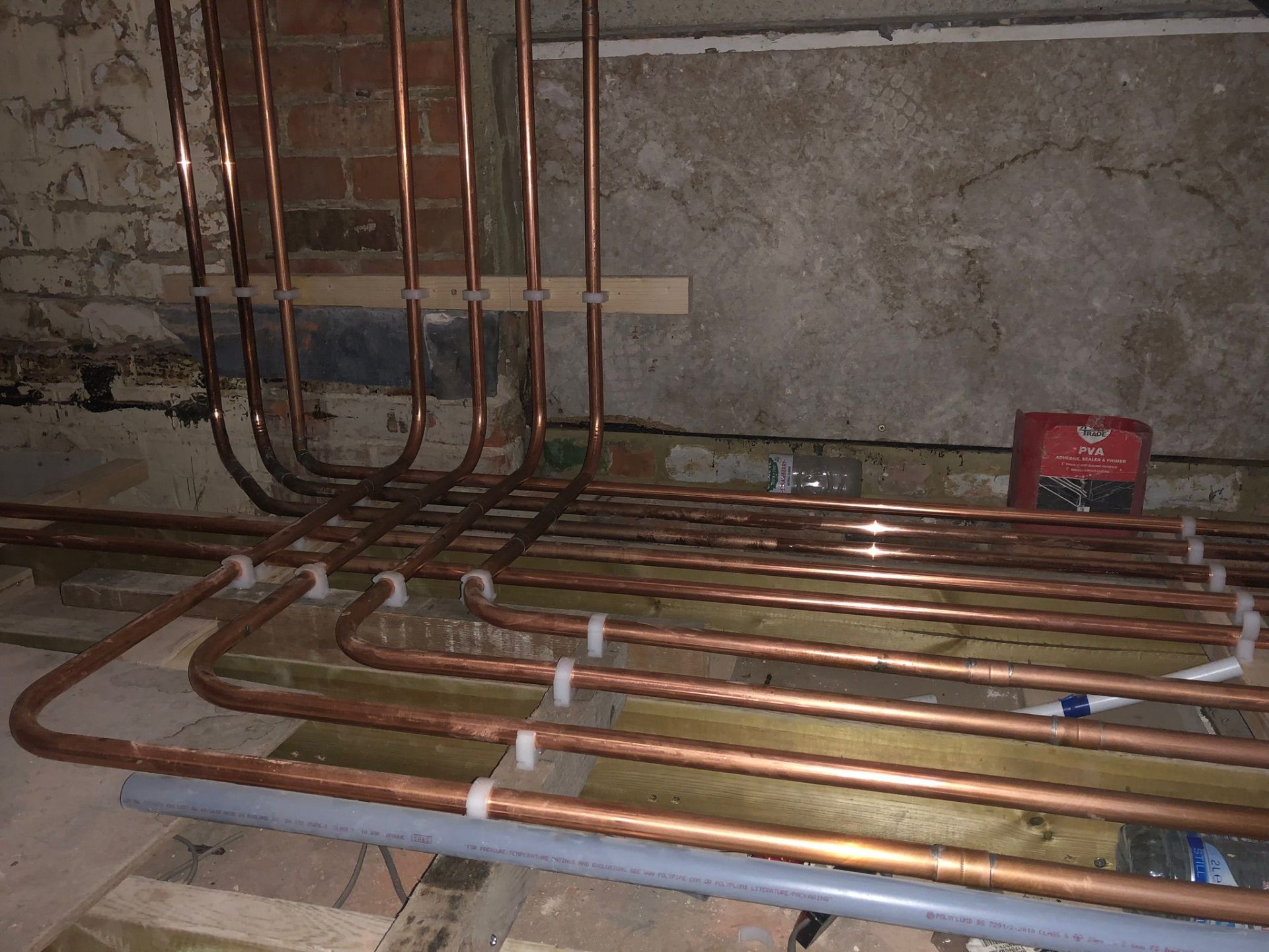 First-fix copper plumbing loops installed beneath a suspended timber floor