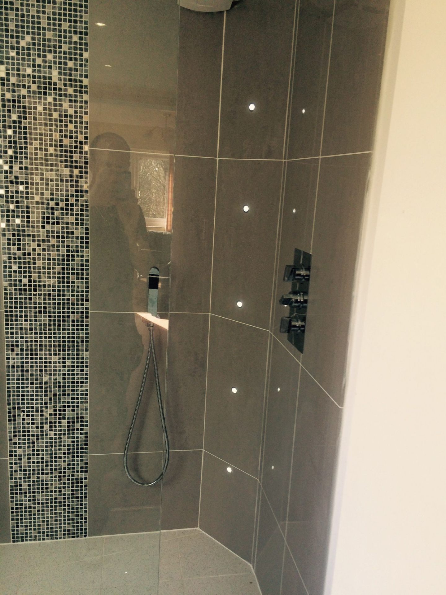 Grey porcelain tiled shower enclosure with mosaic feature strip and integrated LED spotlights