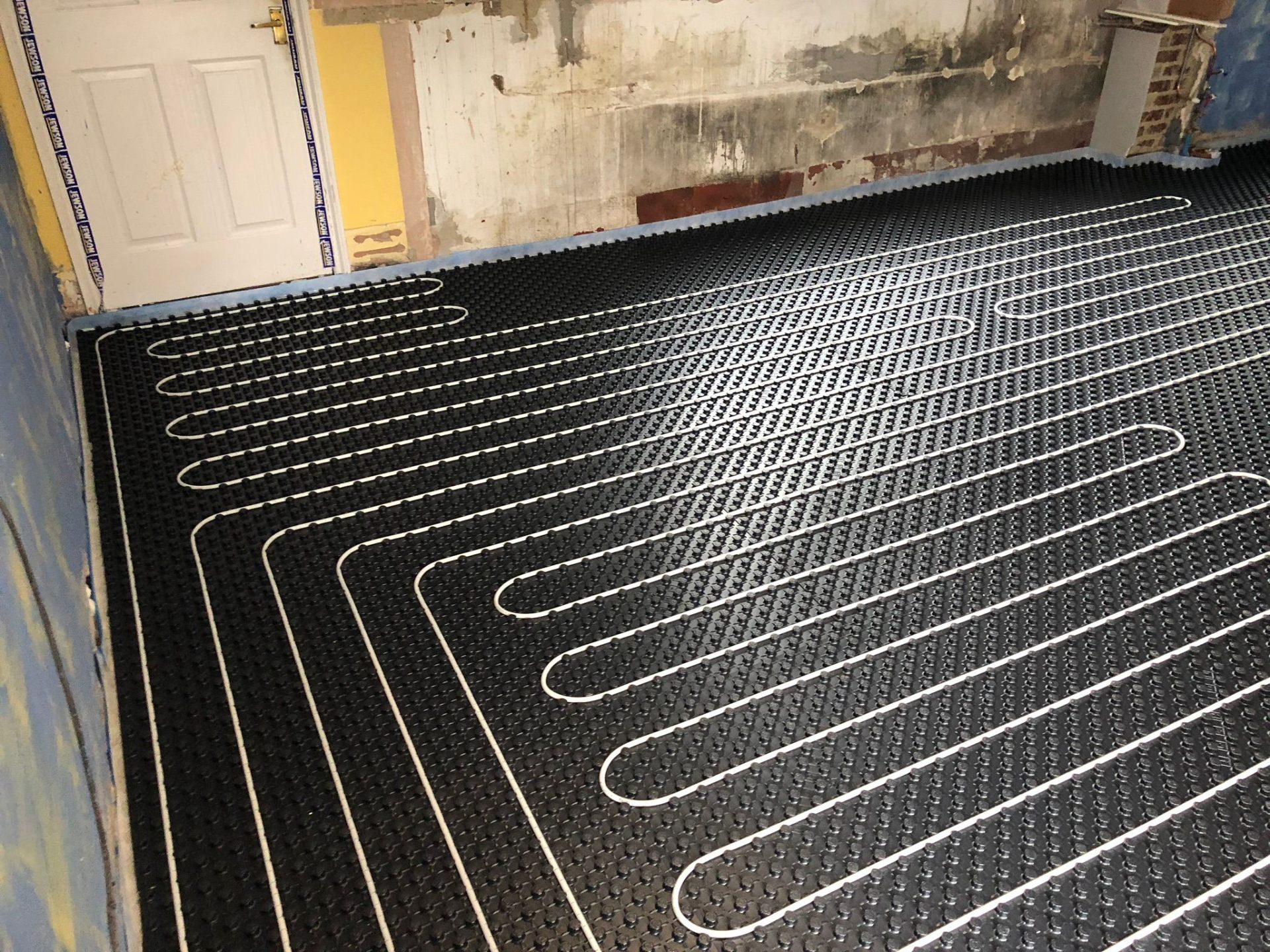 Copper pipework being brazed in situ beneath floor joists during an underfloor heating first-fix