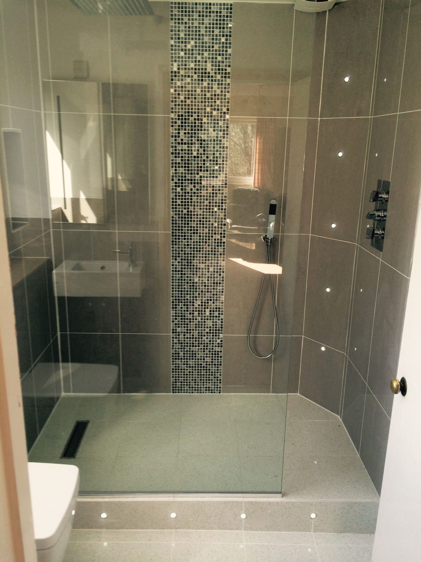 Walk-in wet room with grey porcelain tiles, mosaic feature wall and glass shower screen