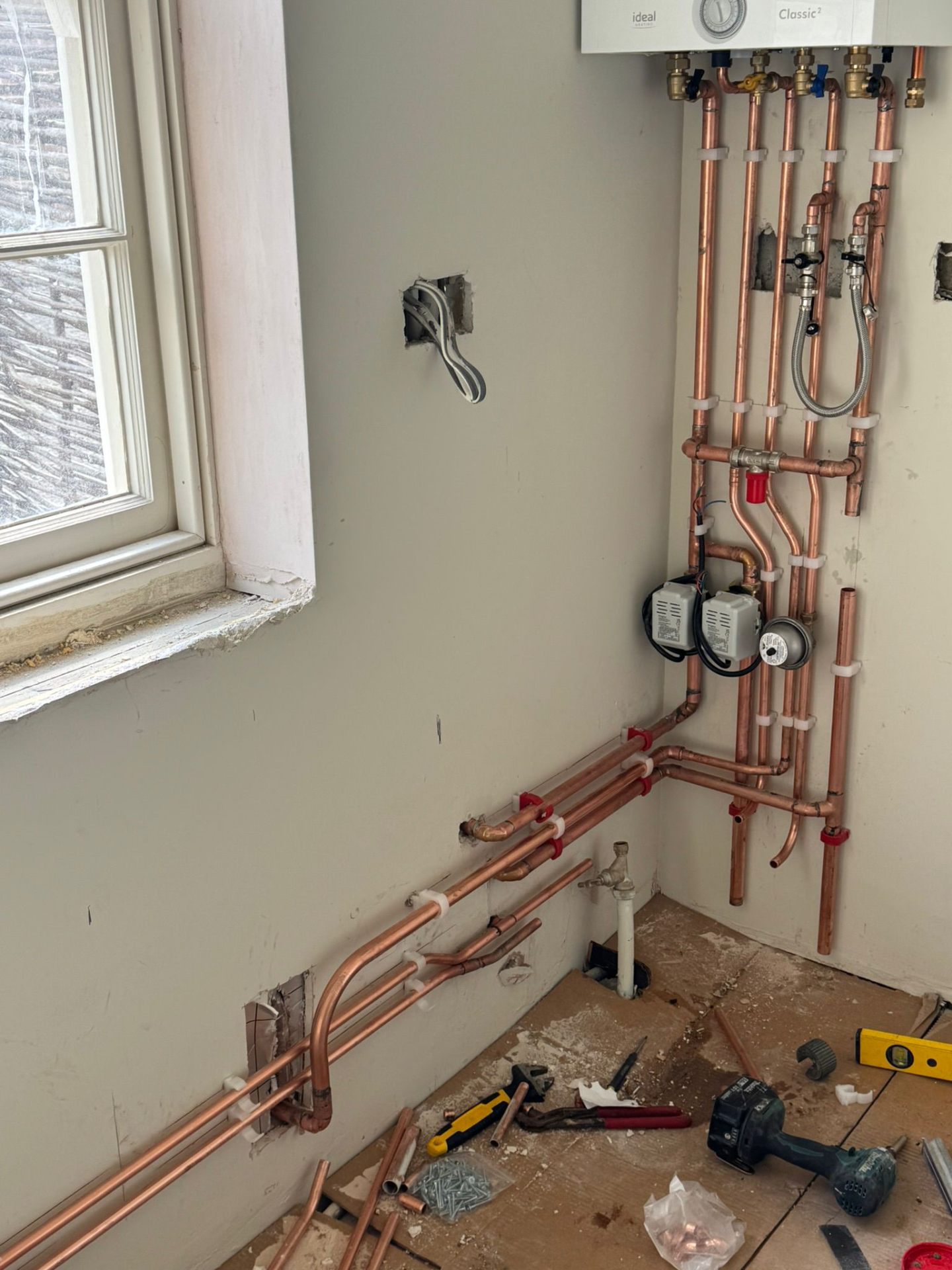 First-fix copper central heating pipework routed cleanly through timber floor joists