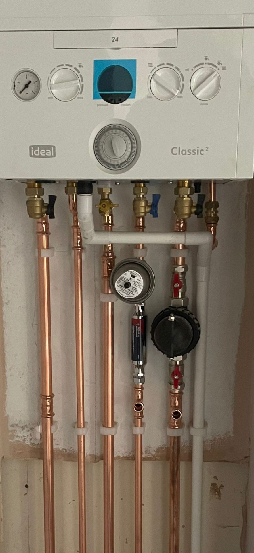 Wall-hung gas boiler alongside an unvented hot water cylinder with tidy copper pipework