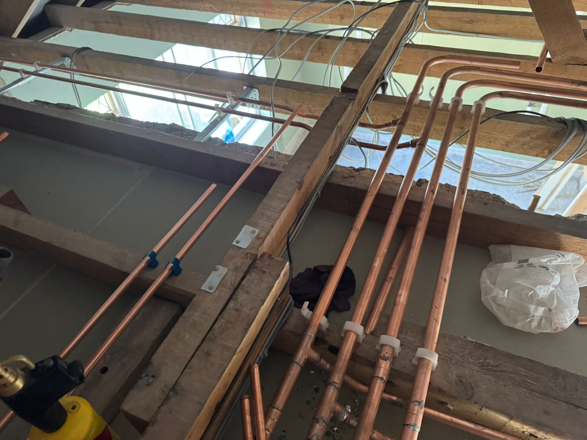 Copper heating and mains pipework installed across loft rafters ready for insulation