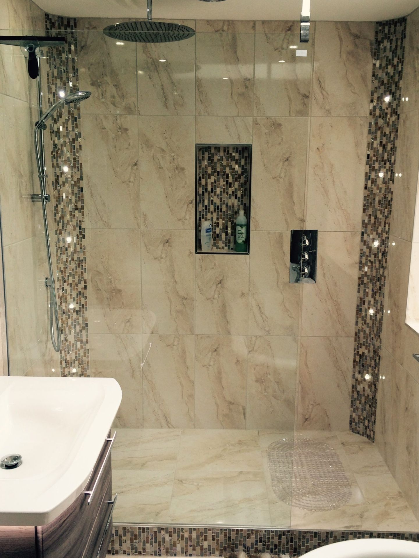 Marble-effect tiled walk-in shower with mosaic feature strip and rainfall shower head
